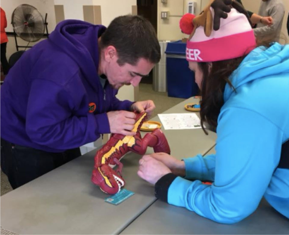 A man demonstrating how to rewire a toy dinosaur to be switch activated.