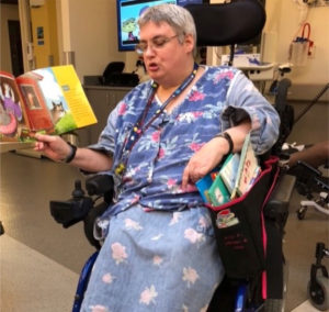 A woman at work reading books to children, in her wheelchair with a book bag that was specially designed for her.